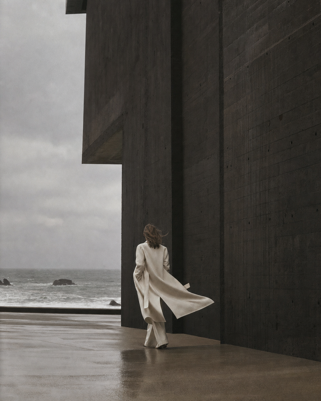A figure in ivory walking through monumental coastal architecture